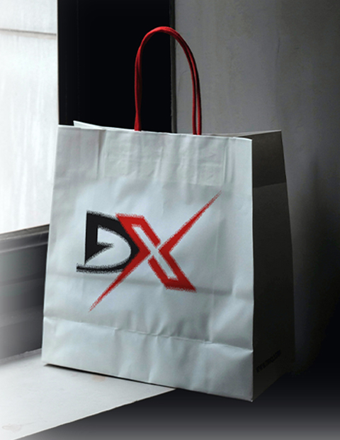 A red-handled white shopping bag next to a window. The DX Men’s Store logo in black and red is printed on the front. Digital Marketer